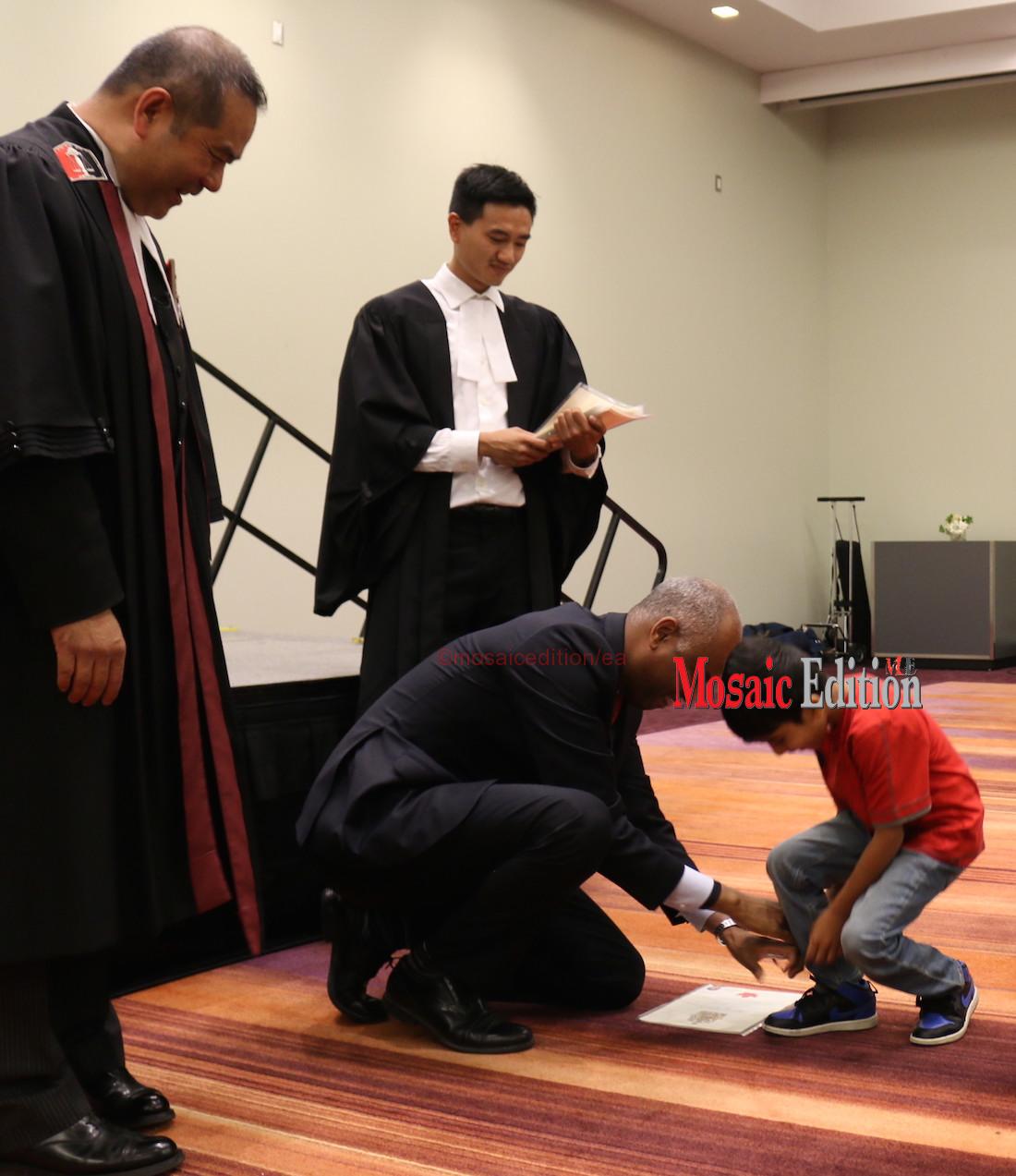 Immigration Minister Hussen helps new Canadian tie shoelace